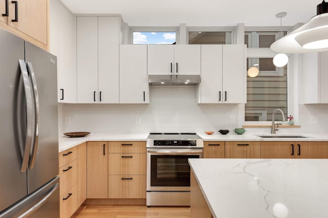 kitchen with light wood-type flooring, stainless steel appliances, sink, decorative light fixtures, and white cabinets