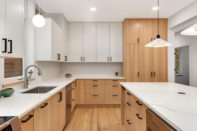 kitchen featuring sink, white cabinets, pendant lighting, and light hardwood / wood-style floors