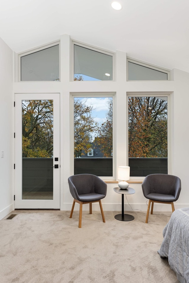 living area featuring light colored carpet, plenty of natural light, and lofted ceiling