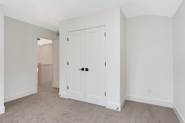 unfurnished bedroom featuring light carpet and a closet