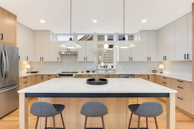 kitchen with a center island, white cabinets, light wood-type flooring, and appliances with stainless steel finishes