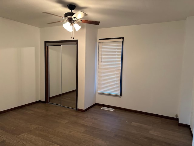 unfurnished bedroom with dark wood-type flooring, ceiling fan, and a closet