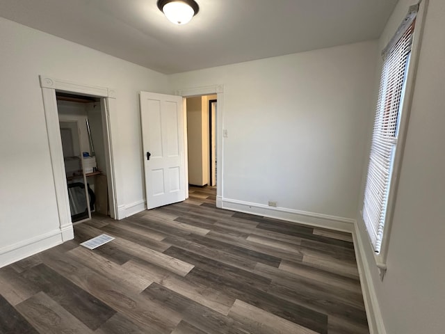 unfurnished bedroom with a closet, multiple windows, and dark hardwood / wood-style floors