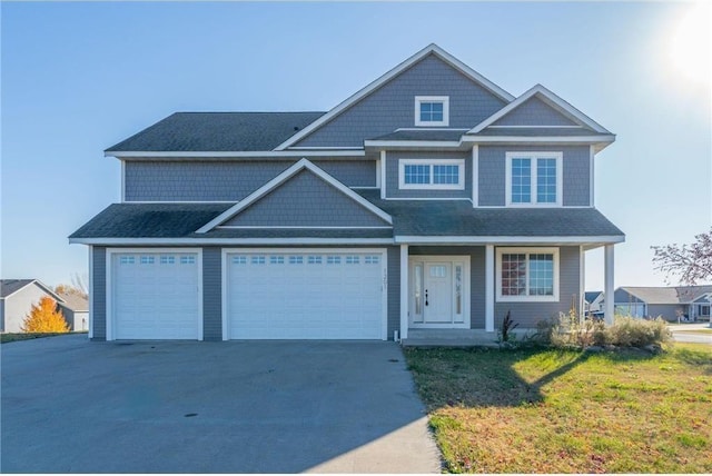 view of front of home featuring covered porch, a garage, and a front lawn