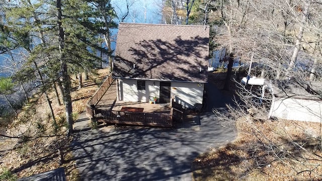 exterior space with a wooden deck and roof with shingles