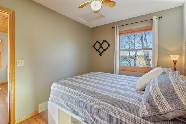 bedroom featuring ceiling fan, attic access, light wood-type flooring, and baseboards