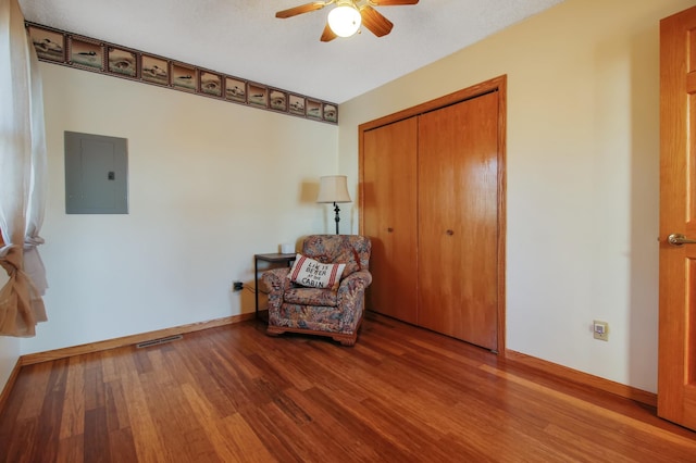 unfurnished room with visible vents, electric panel, wood finished floors, baseboards, and ceiling fan