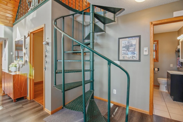 stairway featuring baseboards, a textured ceiling, and wood finished floors