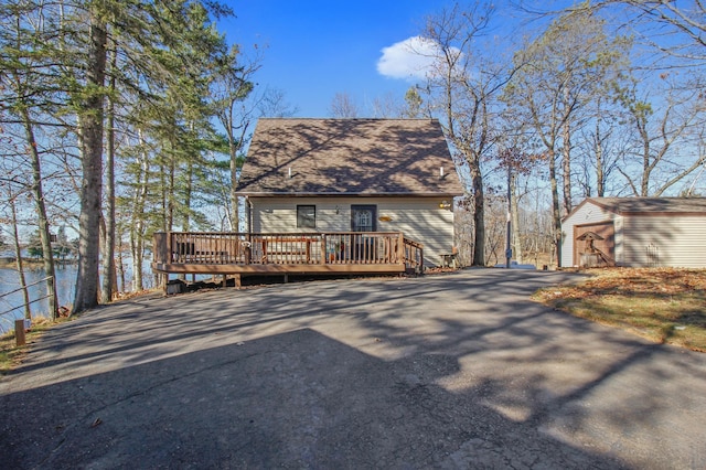 view of front facade featuring a deck, an outbuilding, a garage, and driveway