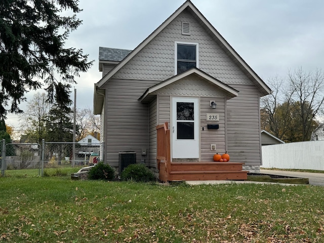 rear view of house featuring central AC unit and a lawn