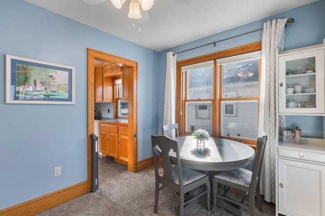 dining space featuring ceiling fan, light colored carpet, and a textured ceiling