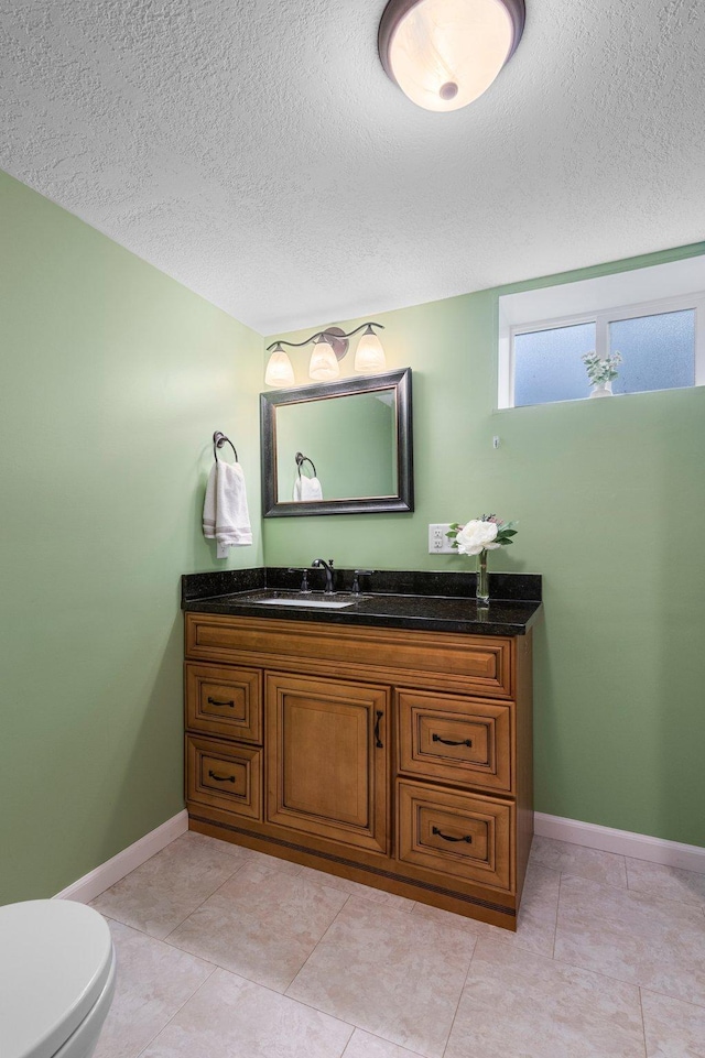 bathroom featuring vanity, toilet, tile patterned flooring, and a textured ceiling