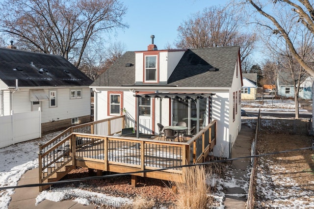 snow covered back of property with a wooden deck