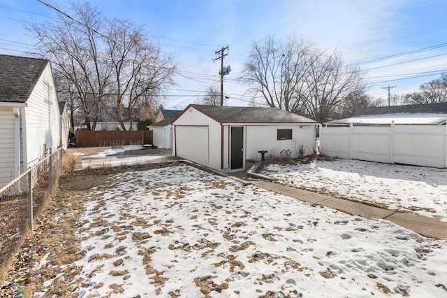 snowy yard featuring an outbuilding and a garage