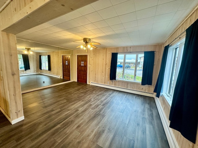 empty room with ceiling fan, wood walls, a baseboard radiator, and dark hardwood / wood-style floors