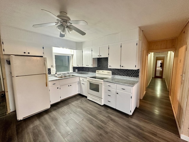 kitchen with dark hardwood / wood-style flooring, wood walls, white cabinetry, and white appliances