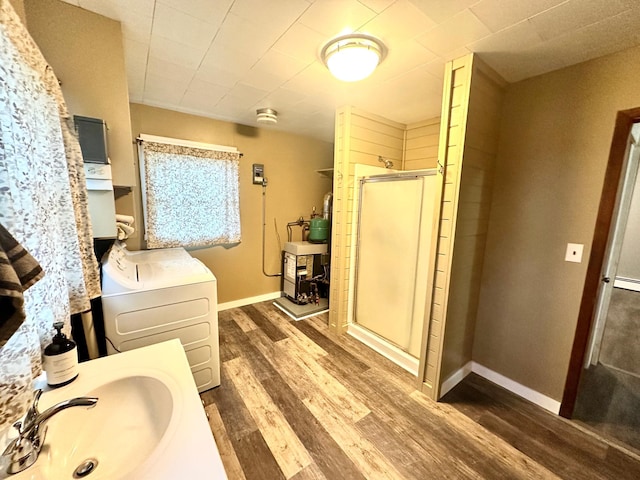30 3rd St, Cohasset, MN 55721 - bathroom with baseboards, a shower stall, vanity, wood finished floors, and washer / dryer