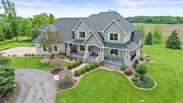 craftsman inspired home featuring a porch and a front yard