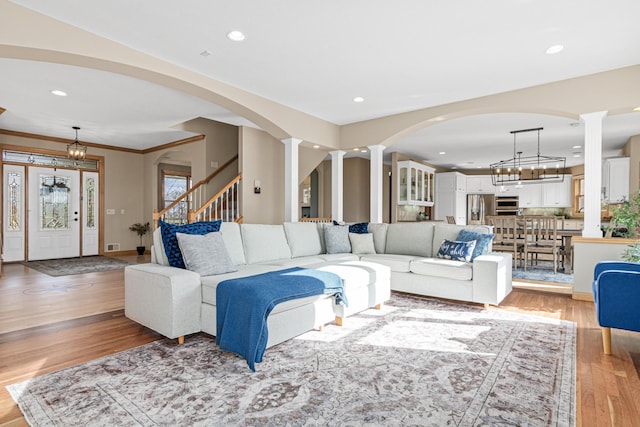 living room with light hardwood / wood-style flooring, crown molding, and a notable chandelier