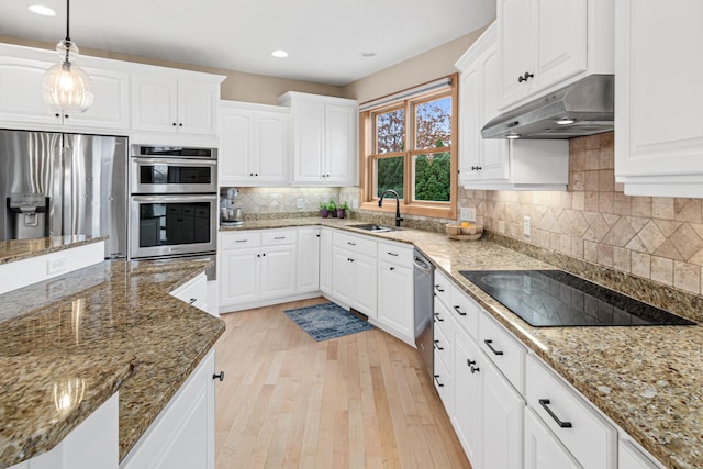 kitchen with white cabinetry, light wood-type flooring, stainless steel appliances, and dark stone counters