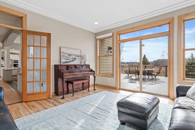 living area with ornate columns, light hardwood / wood-style flooring, and crown molding