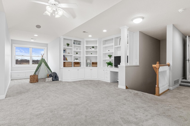 living room featuring ceiling fan, built in desk, and light colored carpet