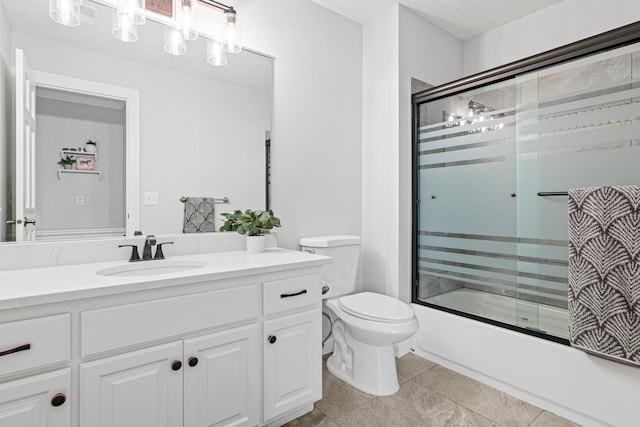 full bathroom featuring a textured ceiling, combined bath / shower with glass door, vanity, tile patterned floors, and toilet