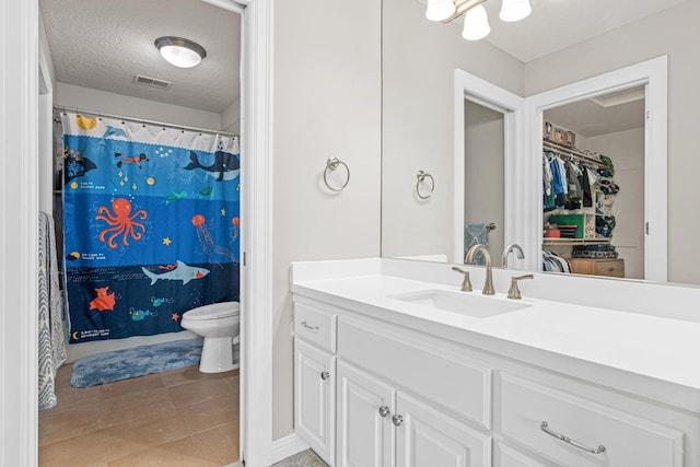 bathroom featuring toilet, vanity, a textured ceiling, and tile patterned flooring