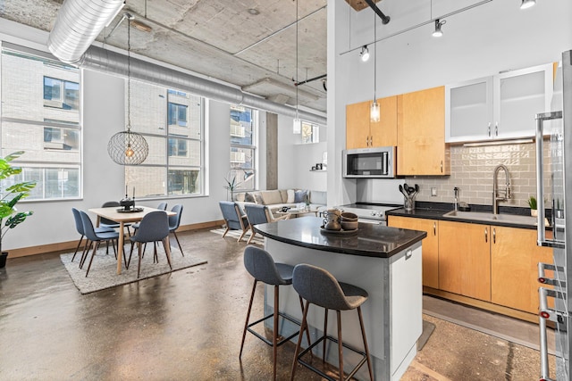 kitchen featuring stainless steel appliances, a kitchen bar, sink, and a wealth of natural light