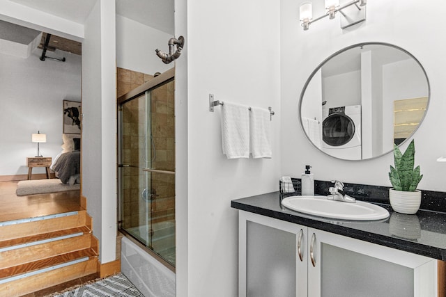 bathroom featuring vanity, stacked washer and clothes dryer, and shower / bath combination with glass door