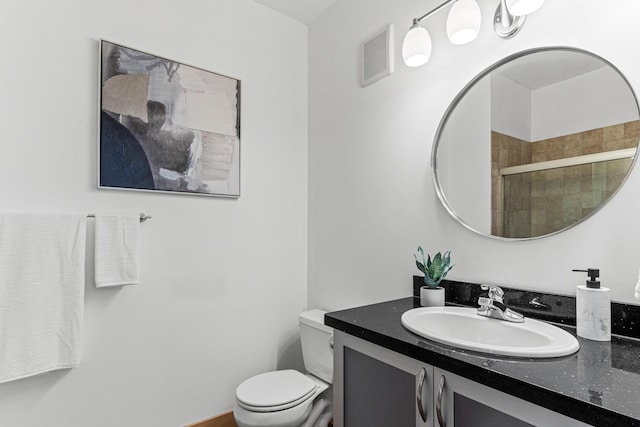 bathroom with vanity, a shower with shower door, and toilet