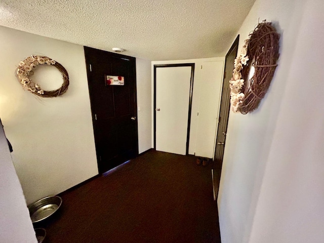 corridor with carpet flooring and a textured ceiling