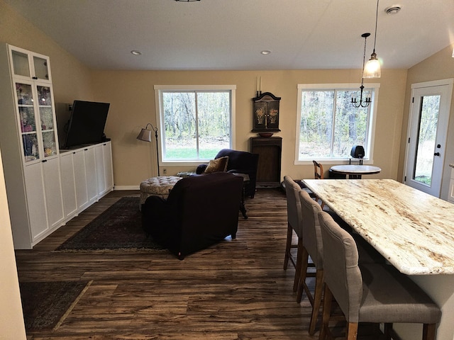 dining area with dark hardwood / wood-style flooring, a chandelier, and vaulted ceiling