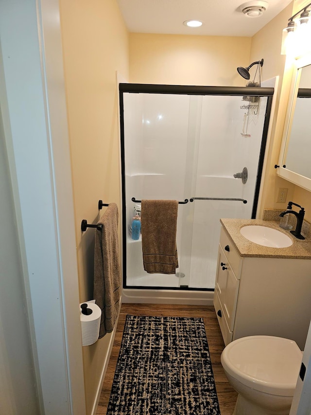 bathroom with walk in shower, vanity, hardwood / wood-style flooring, and toilet