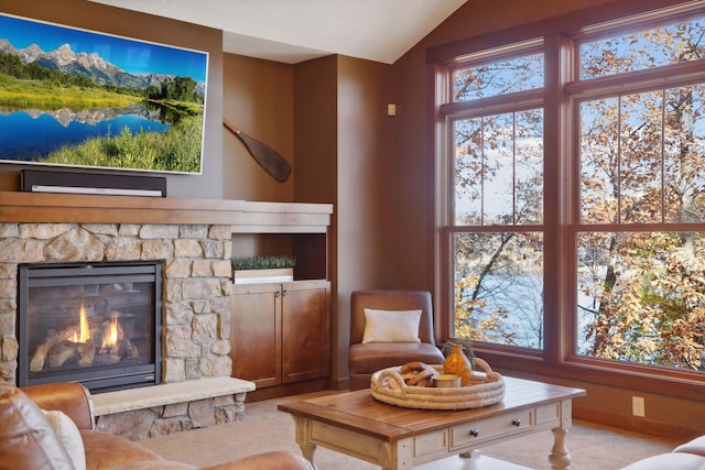 carpeted living room with a stone fireplace, a water view, and lofted ceiling