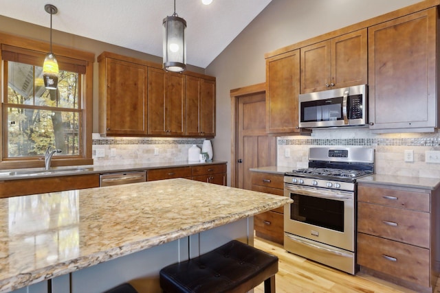 kitchen with sink, appliances with stainless steel finishes, a kitchen bar, backsplash, and lofted ceiling