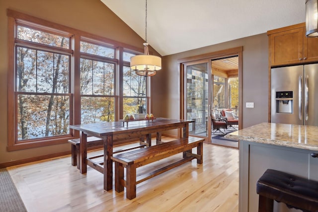 dining room with light hardwood / wood-style floors, a healthy amount of sunlight, and vaulted ceiling