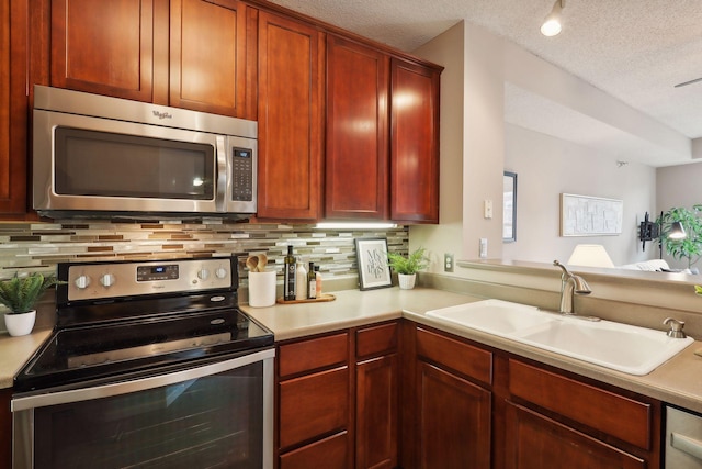 kitchen featuring sink, stainless steel appliances, tasteful backsplash, kitchen peninsula, and a textured ceiling