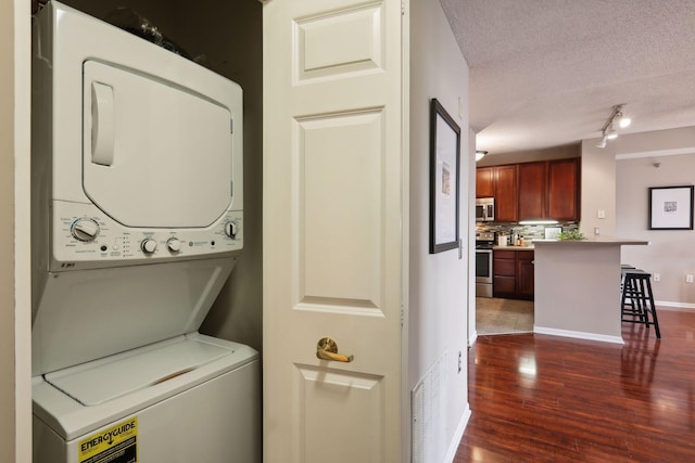 clothes washing area featuring stacked washer / drying machine, dark hardwood / wood-style floors, and a textured ceiling