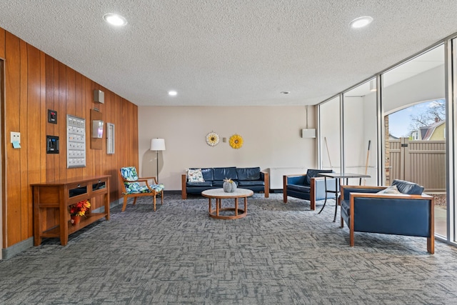 living room with carpet, wood walls, and a textured ceiling