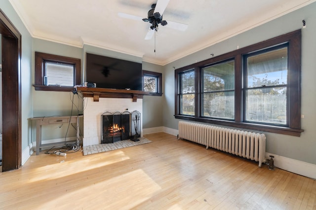 unfurnished living room with ceiling fan, wood-type flooring, radiator heating unit, and a brick fireplace