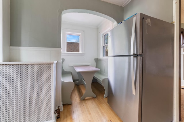 kitchen featuring light hardwood / wood-style floors, crown molding, and stainless steel refrigerator