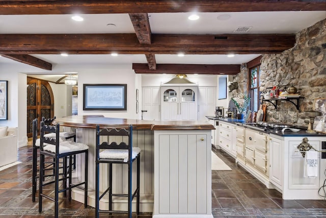 kitchen with a kitchen breakfast bar, white cabinets, beam ceiling, and a kitchen island