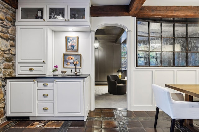 bar featuring beam ceiling and white cabinets