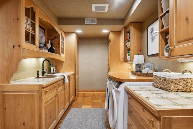 clothes washing area featuring sink, light tile patterned flooring, and independent washer and dryer