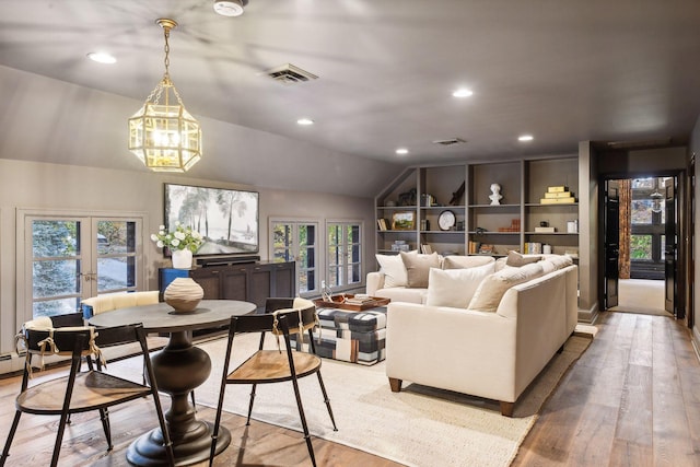 living room with light hardwood / wood-style flooring, french doors, a chandelier, and lofted ceiling