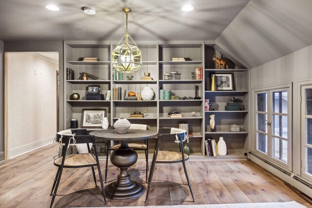 dining space featuring a healthy amount of sunlight, hardwood / wood-style flooring, lofted ceiling, and a baseboard heating unit