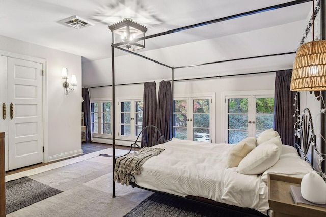 bedroom featuring hardwood / wood-style floors, french doors, a baseboard heating unit, and access to exterior