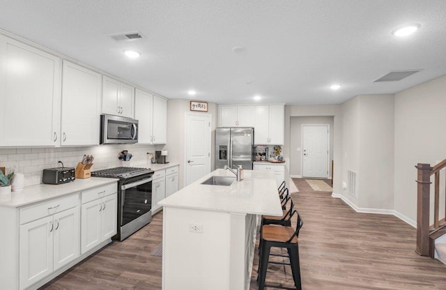 kitchen featuring sink, dark hardwood / wood-style floors, an island with sink, white cabinetry, and stainless steel appliances