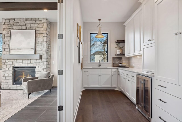 interior space featuring tasteful backsplash, wine cooler, white cabinets, and a sink